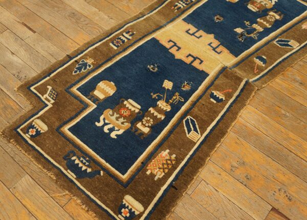 A dark blue and brown runner rug with stylized vessel patterns rests on distressed wooden floorboards.