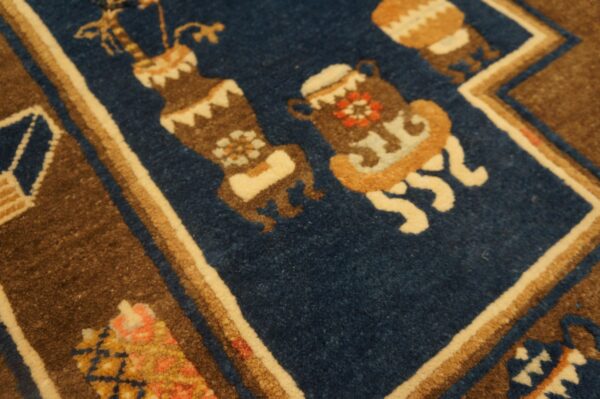 Detailed view of a rug showing brown, cream, and blue stylized vase motifs with thick pile texture.