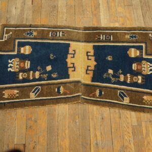 Stepped blue and brown area rug featuring stylized vessels and a central tan panel on weathered wood floor.