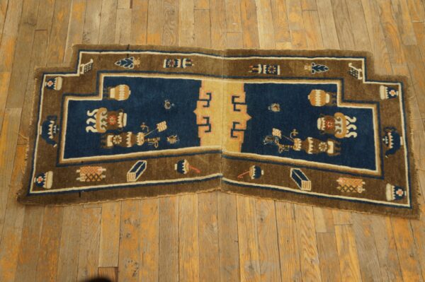 Stepped blue and brown area rug featuring stylized vessels and a central tan panel on weathered wood floor.