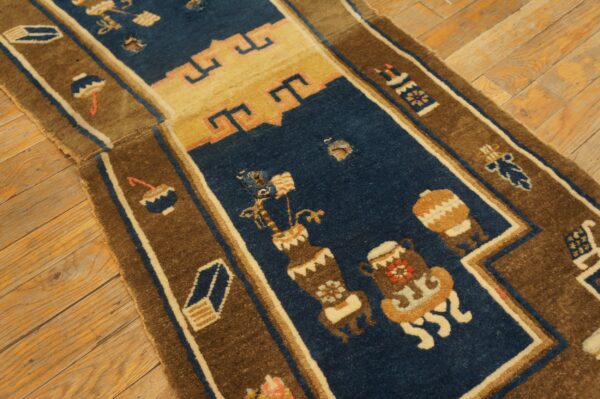 Close-up of a damaged blue and brown patterned rug with holes exposing the wooden floor underneath.