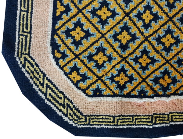 Close-up shows a multi-colored rug with a navy, mustard yellow, and light blue geometric center pattern.
