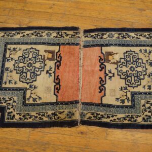 Stepped rug halves featuring cream fields, coral centers, and detailed blue patterns rest on polished wood planks.