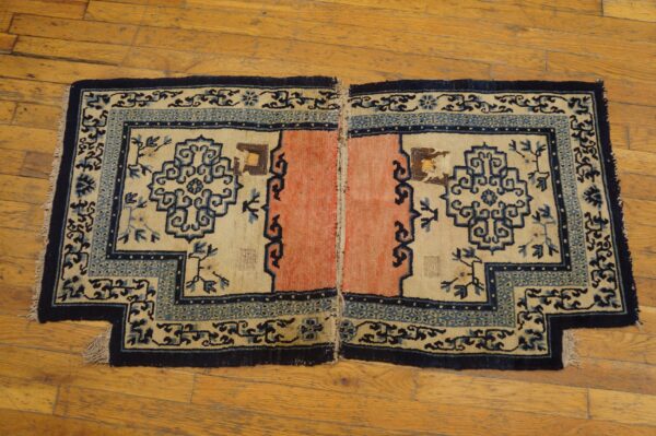 Stepped rug halves featuring cream fields, coral centers, and detailed blue patterns rest on polished wood planks.