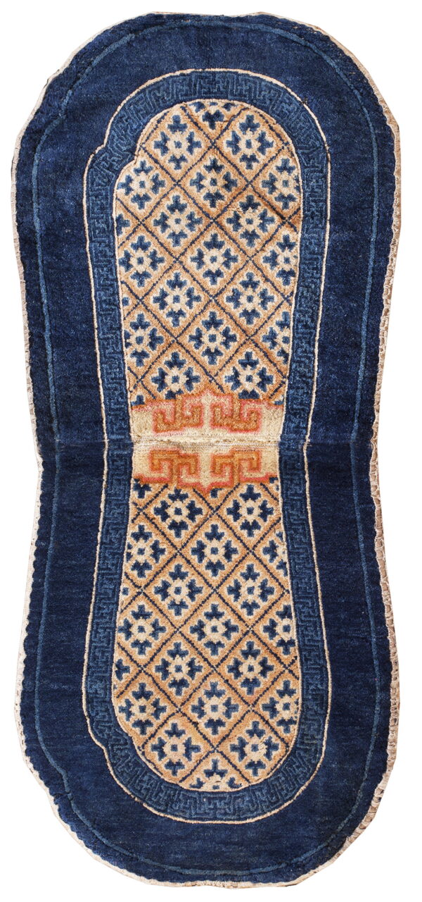 Oblong blue rug with rounded ends, featuring a tan diamond pattern and reddish-orange central detail.