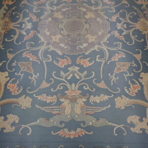 Muted blue rug with a traditional design featuring ornate dragons, scrolling vines, and flowers.
