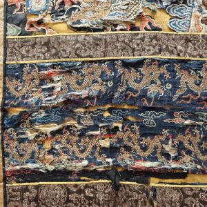 Distressed textile showing horizontal bands of embroidered golden dragons on dark blue, bordered by tan and brown fabric.