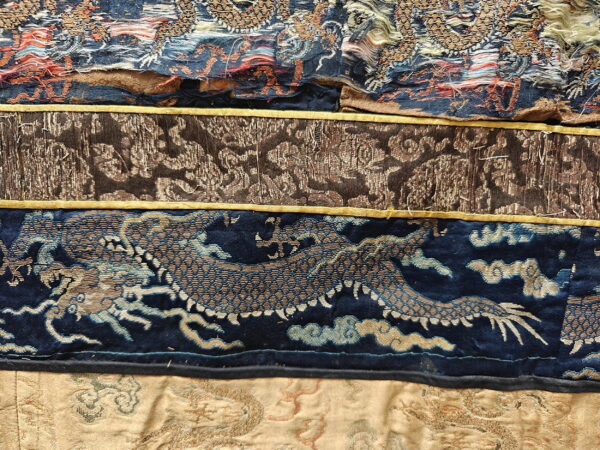 Close-up shows layered textiles: gold and blue dragon weave, brown patterned fabric, and textured beige cloth.