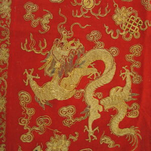 Red textile detailed with a gold embroidered dragon, swirling clouds, and traditional floral patterns.