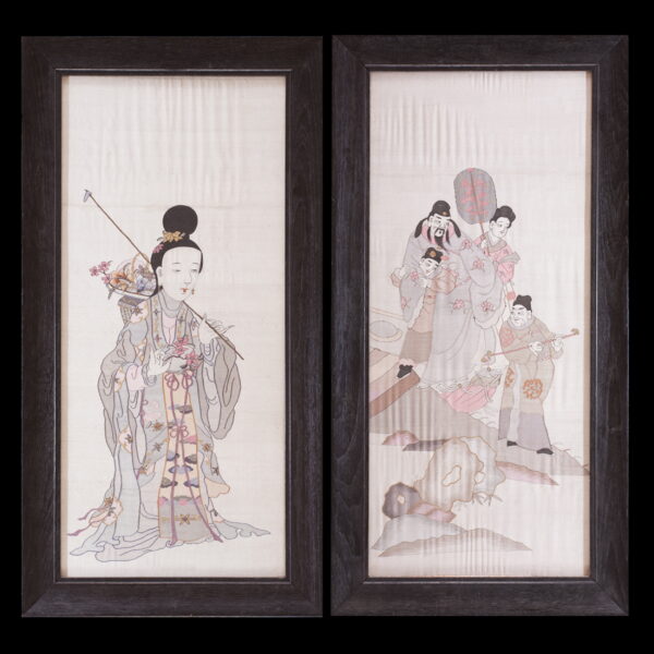Framed pair of panels display detailed figures in soft gray, pink, and mauve embroidery on pale fabric.