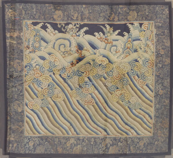 Muted blue and gold textile displaying stylized ocean waves, foam, and cloud motifs within a patterned border.