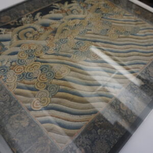 Ornate rug sample displaying a central diamond pattern of waves and clouds with a dark floral border.