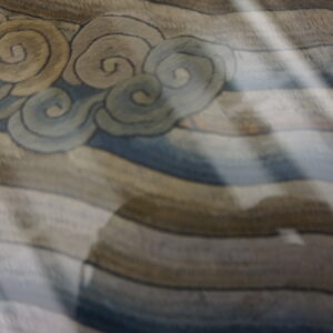 Muted beige and blue cloud-patterned rug texture with strong diagonal light and a large central shadow.