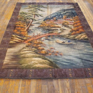 Scenic rug with a river, bridge, and autumn foliage bordered by dark brown pattern on wood floor.