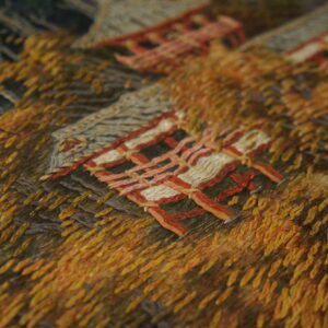 Detailed texture of a rug with dense yellow and orange stitching surrounding woven geometric shapes.