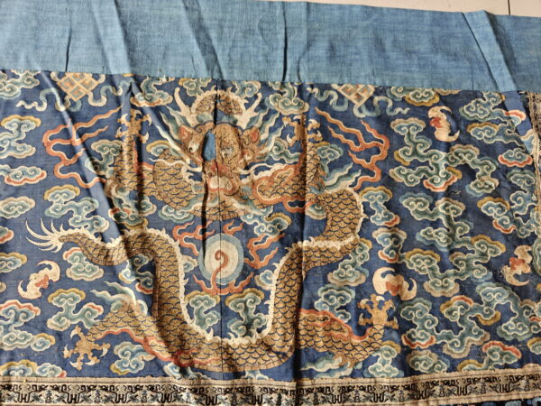 Low-pile textile in dark blue with a large metallic gold dragon and swirling rust and light blue clouds.