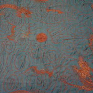 Flat teal textile featuring a rust-orange pattern of dragons, swirling clouds, and a central orb.