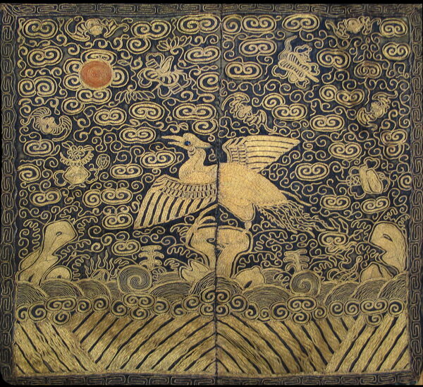 Blue rug with dense gold patterning featuring a large winged bird, sun disc, clouds, and waves.