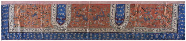 Rust and cobalt blue embroidered textile showing detailed scenes of figures and a large central dragon.