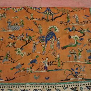 Low-pile orange textile featuring detailed embroidery of figures, a blue creature, a pavilion, and a cream floral border.