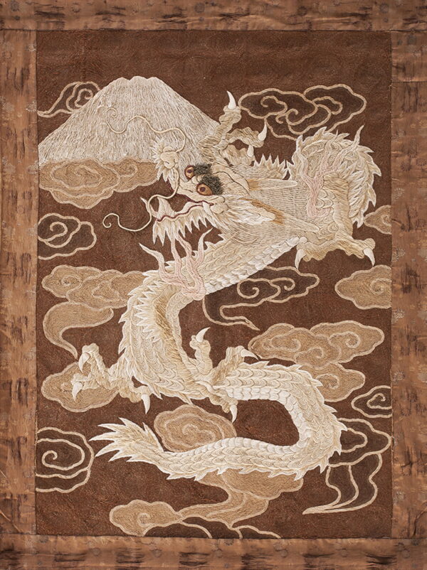 Textured brown textile featuring a large cream dragon, mountain, and stylized cloud pattern.