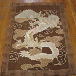 Low-pile brown rug featuring a large cream-colored dragon and mountain pattern rests on wood flooring.