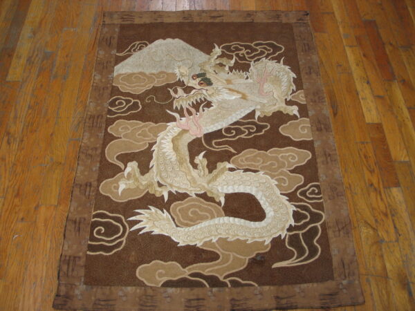 Low-pile brown rug featuring a large cream-colored dragon and mountain pattern rests on wood flooring.