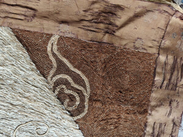Close detail of a brown looped rug with light curved patterns adjacent to a section of long, shaggy beige pile.