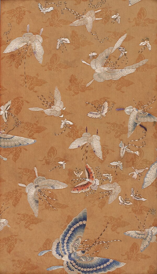 Camel textile displaying an all-over embroidered pattern of white, blue, and coral flying moths and butterflies.