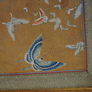 Gold field rug with blue and white insect motifs, surrounded by a complex geometric tile border.