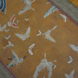 Gold runner rug with an overall pattern of white and blue flying insects and a geometric border on a wood floor.