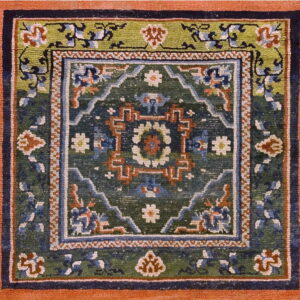 Square rug with a wide terracotta border framing complex geometric patterns in green, navy, and rust.