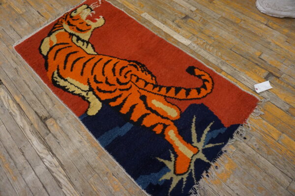 Orange, tan, and black tiger rug on a red and navy background resting on rustic wood floors.
