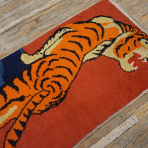Rust and navy rug featuring a stylized orange tiger design, laid across rustic wood floorboards.