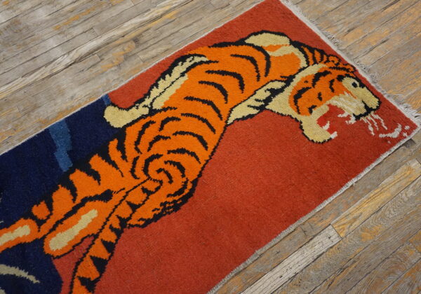 Rust and navy rug featuring a stylized orange tiger design, laid across rustic wood floorboards.