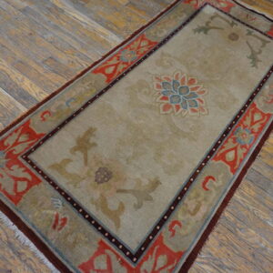 Beige runner rug with blue and coral central medallion and rust border on distressed wood planks.