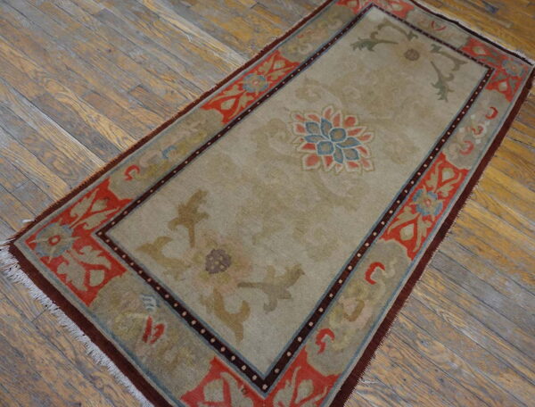 Beige runner rug with blue and coral central medallion and rust border on distressed wood planks.