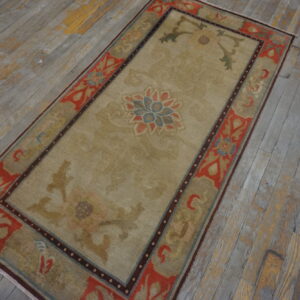 Beige and coral floral-patterned runner rug lying on distressed grey wooden plank flooring.