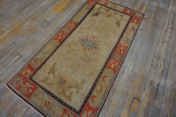 Beige and coral floral-patterned runner rug lying on distressed grey wooden plank flooring.