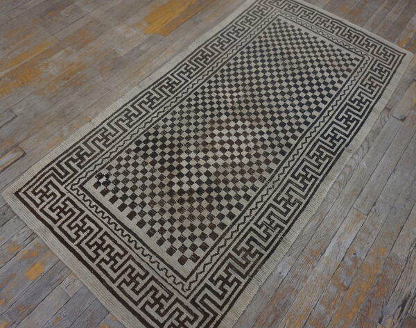 Low-pile runner with a checkered dark brown and tan design on distressed wooden planks.