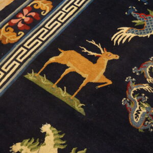 Detail of a blue rug showing a tan deer, patterned dragons, and a geometric and floral border on wood flooring.