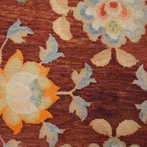 Close-up shows large cream, orange, and light blue floral designs on a deep red field.