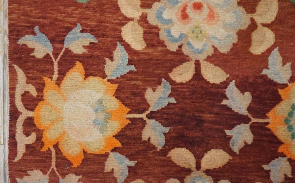 Close-up shows large cream, orange, and light blue floral designs on a deep red field.