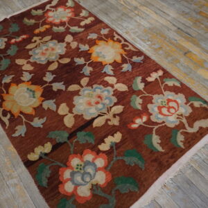 Deep red-brown rug with stylized flowers in blue, green, and orange on weathered wood planks.