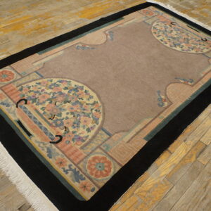 Mauve Art Deco rug with large pastel floral medallions and a thick black border on rustic hardwood.