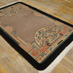 Rectangular rug featuring a brown center field, black border, and multi-colored floral accents on worn wood.