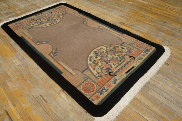 Rectangular rug featuring a brown center field, black border, and multi-colored floral accents on worn wood.