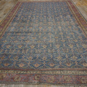 Blue and red distressed rug featuring an all-over floral trellis pattern on rustic wooden flooring.