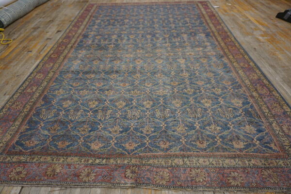 Blue and red distressed rug featuring an all-over floral trellis pattern on rustic wooden flooring.