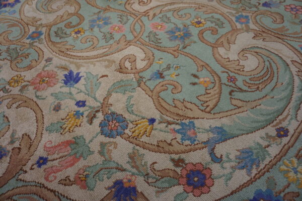 Ornate rug pattern with large brown scrolls, light teal ground, beige accents, and colorful flowers.